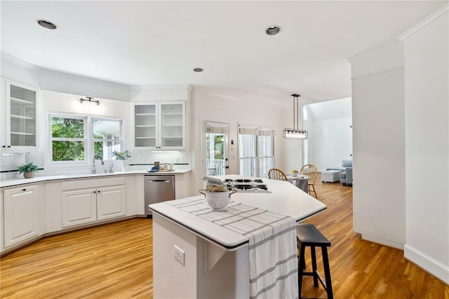 kitchen with stainless steel dishwasher, a kitchen island, a breakfast bar, light wood-type flooring, and white cabinetry