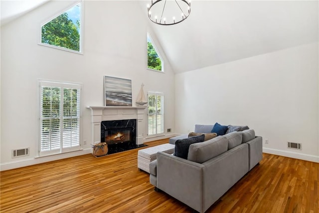 living room featuring an inviting chandelier, high vaulted ceiling, wood finished floors, and visible vents