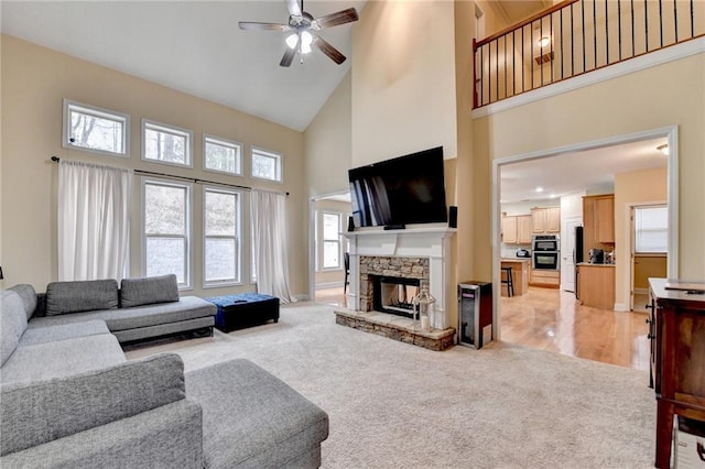 carpeted living room featuring ceiling fan, a stone fireplace, and high vaulted ceiling