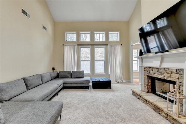 carpeted living room featuring a fireplace and high vaulted ceiling