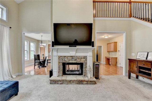 living room with light colored carpet, a fireplace, and a towering ceiling