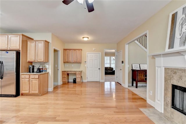 kitchen with a fireplace, stainless steel fridge, light hardwood / wood-style flooring, and light brown cabinets