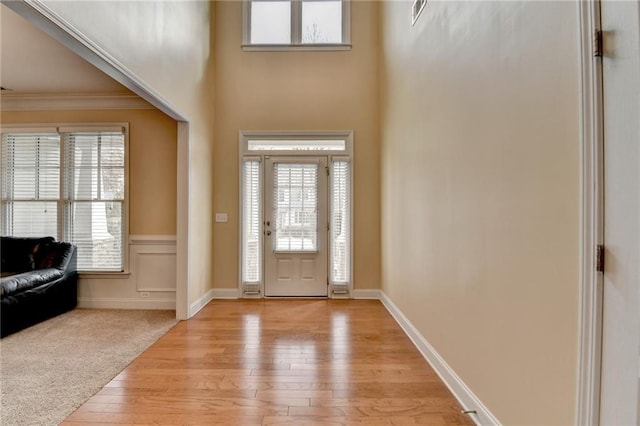 foyer featuring ornamental molding, light hardwood / wood-style floors, and a high ceiling