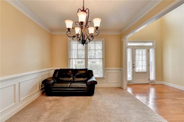 living area featuring crown molding, light colored carpet, and a chandelier