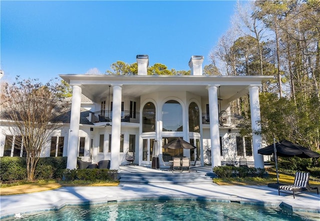 back of house featuring an outdoor pool, a patio, and a balcony