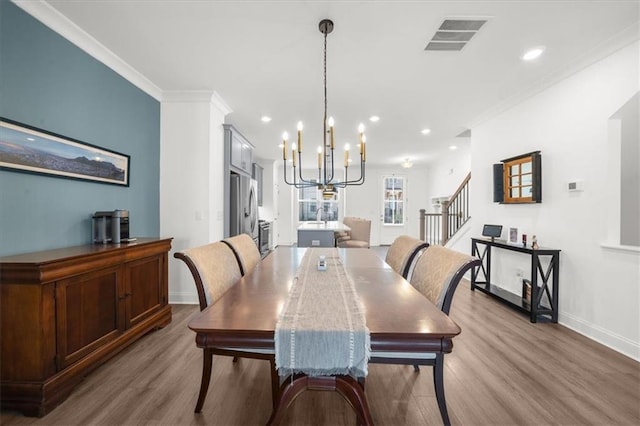 dining room featuring ornamental molding, wood-type flooring, and an inviting chandelier