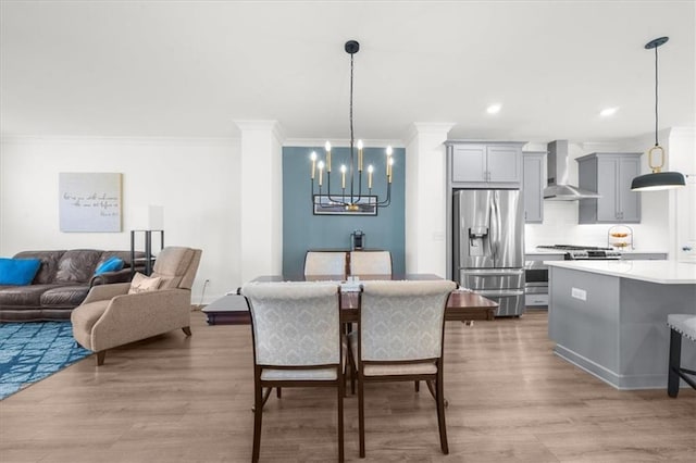 dining space featuring a notable chandelier, crown molding, and light wood-type flooring