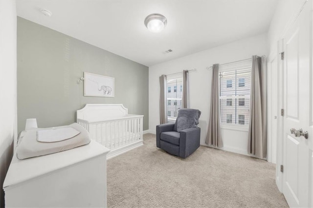 bedroom featuring a nursery area and light colored carpet