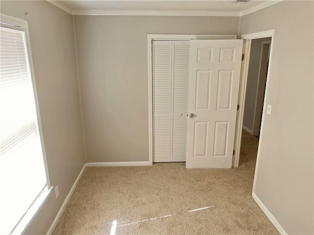 unfurnished bedroom featuring light carpet, crown molding, and a closet