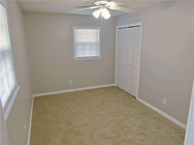 unfurnished bedroom with ceiling fan, multiple windows, a closet, and light carpet