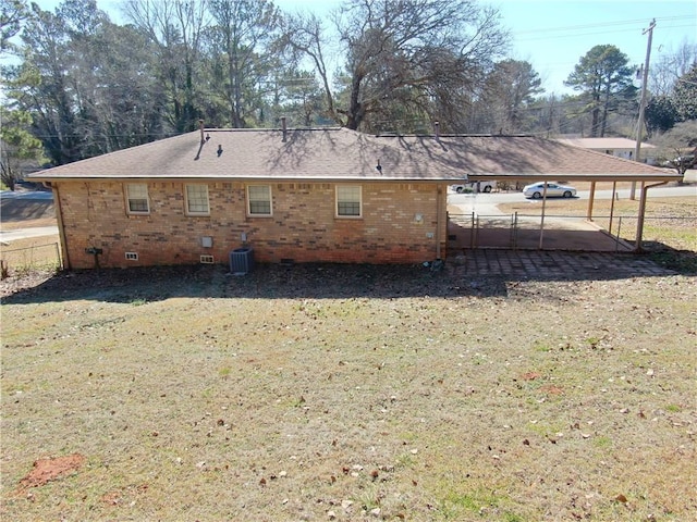 rear view of property featuring central AC and a lawn