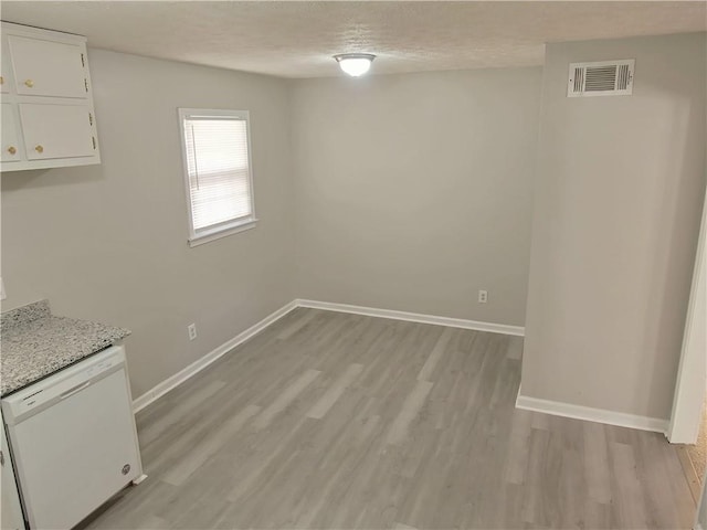 unfurnished dining area with light hardwood / wood-style flooring and a textured ceiling