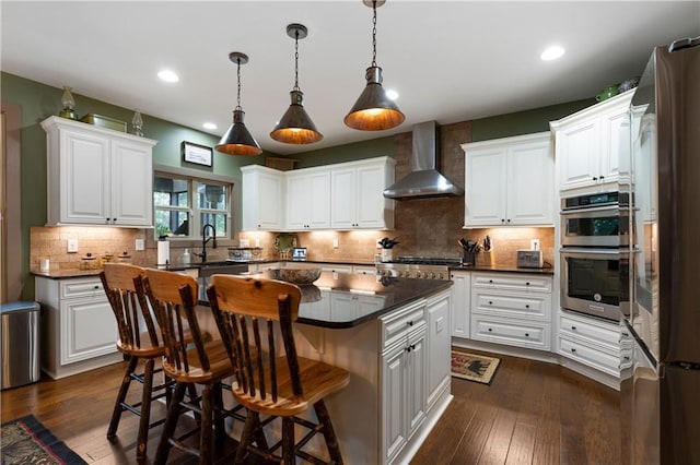 4 Bluff Ct, Cartersville, GA 30120 - kitchen featuring wall chimney range hood, dark countertops, stainless steel double oven, white cabinets, and recessed lighting