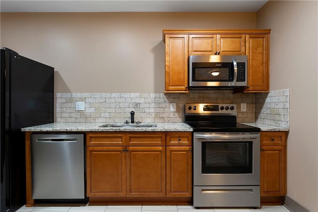 4 Bluff Ct, Cartersville, GA 30120 - kitchen featuring appliances with stainless steel finishes, brown cabinetry, light stone countertops, and decorative backsplash