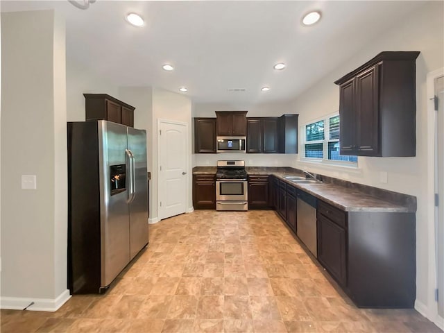 kitchen featuring dark brown cabinets, light tile patterned floors, appliances with stainless steel finishes, and sink