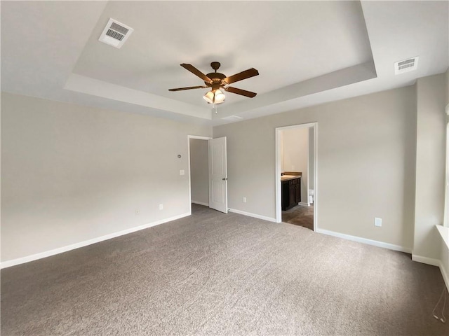 carpeted spare room with a tray ceiling and ceiling fan