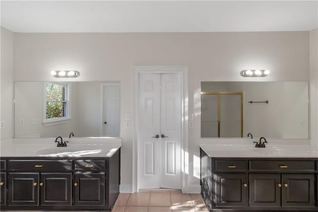 bathroom with two vanities, a sink, a shower stall, tile patterned flooring, and baseboards