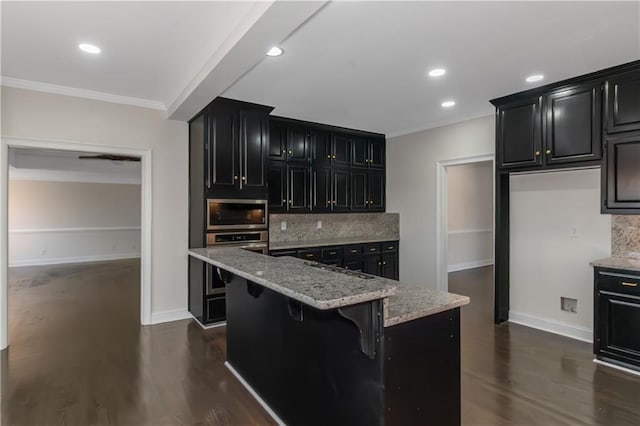 kitchen featuring ornamental molding, dark wood finished floors, stainless steel appliances, decorative backsplash, and dark cabinets