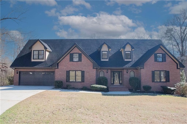 new england style home featuring a garage, driveway, brick siding, and a front yard