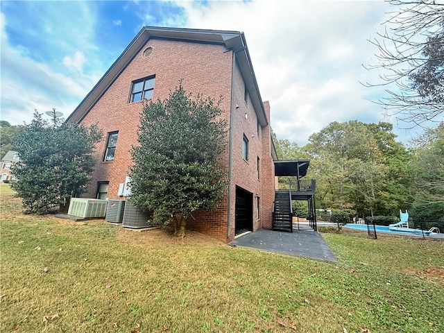 view of side of home featuring stairs, brick siding, an attached garage, and a lawn