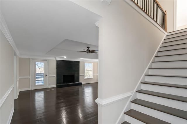 stairs with a fireplace, crown molding, a healthy amount of sunlight, and a ceiling fan