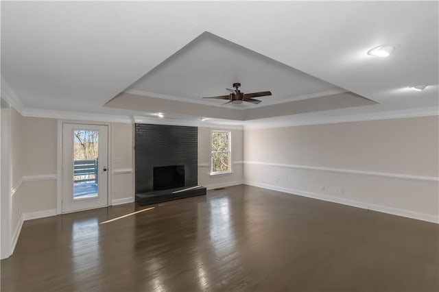 unfurnished living room featuring a large fireplace, a raised ceiling, a healthy amount of sunlight, and crown molding