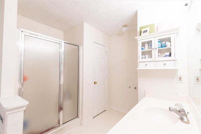 bathroom with vanity, a shower with shower door, and a textured ceiling