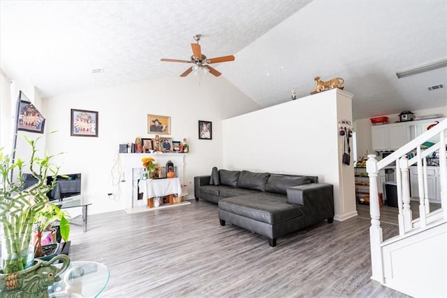 living room featuring a textured ceiling, vaulted ceiling, hardwood / wood-style flooring, and ceiling fan