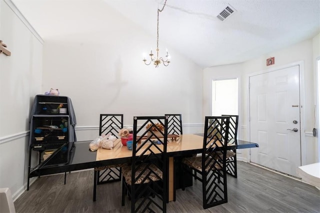 dining area featuring vaulted ceiling, a notable chandelier, and dark hardwood / wood-style floors