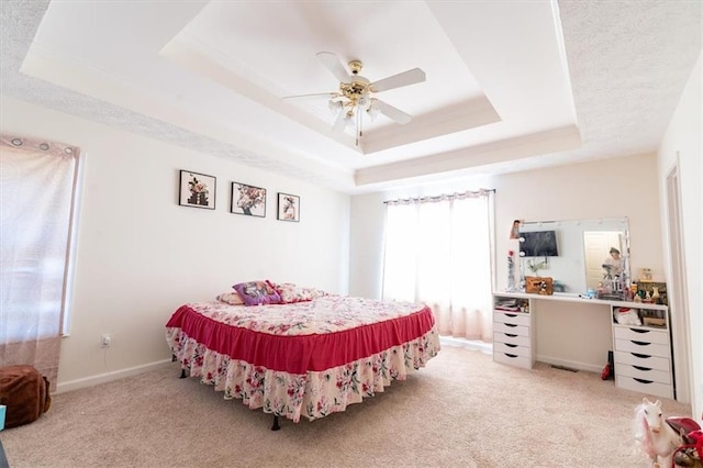 carpeted bedroom with ceiling fan and a tray ceiling