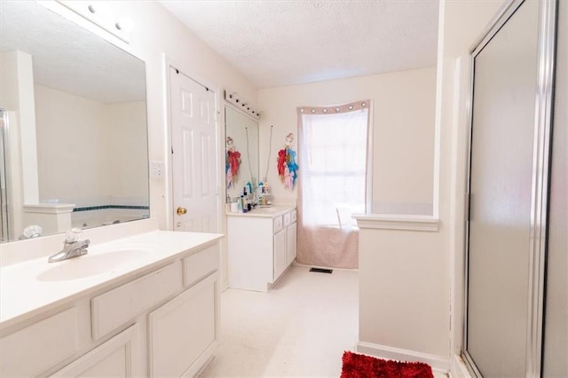 bathroom with vanity, a shower with shower door, and a textured ceiling