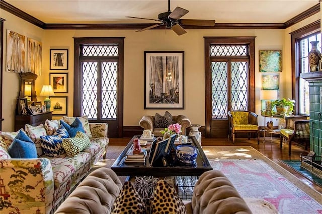 living area with wood finished floors, ornamental molding, and a ceiling fan