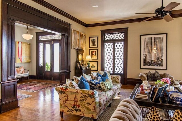 living room featuring crown molding, baseboards, decorative columns, french doors, and wood finished floors