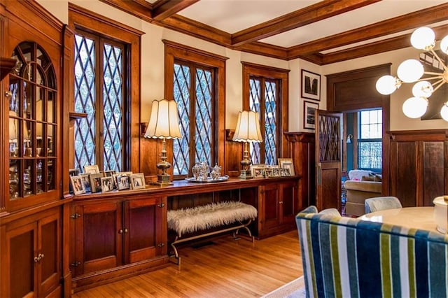 office space with a wainscoted wall, beam ceiling, ornamental molding, wood finished floors, and an inviting chandelier