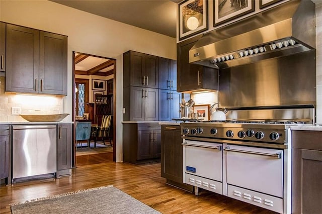 kitchen featuring under cabinet range hood, wood finished floors, appliances with stainless steel finishes, and light countertops