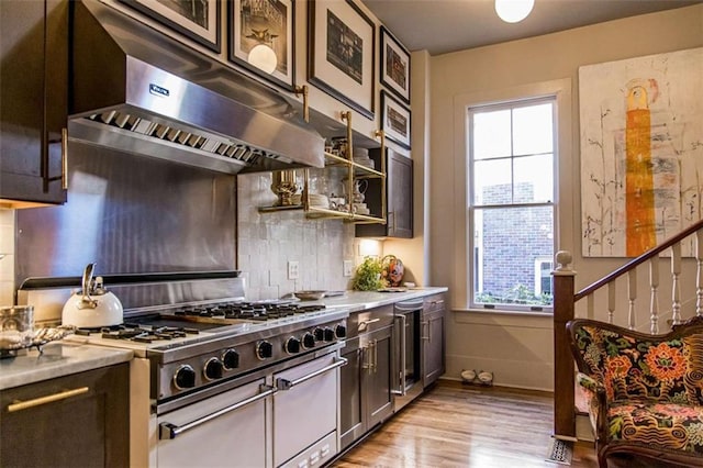 kitchen with backsplash, under cabinet range hood, double oven range, light countertops, and light wood-type flooring