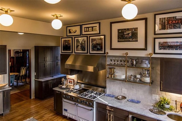 kitchen featuring under cabinet range hood, tasteful backsplash, dark wood-style floors, gas range oven, and dark brown cabinetry