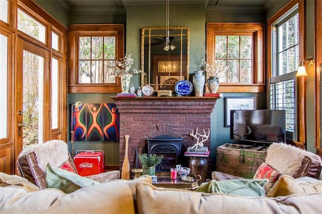 living area with crown molding, a wood stove, and plenty of natural light