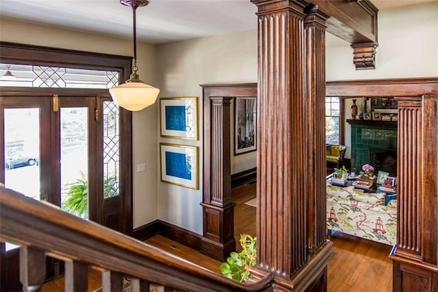 room details with a fireplace, decorative columns, and wood finished floors