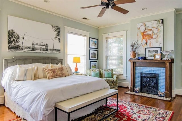 bedroom with a fireplace, crown molding, wood finished floors, and baseboards