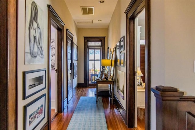 corridor featuring visible vents, baseboards, and dark wood-type flooring