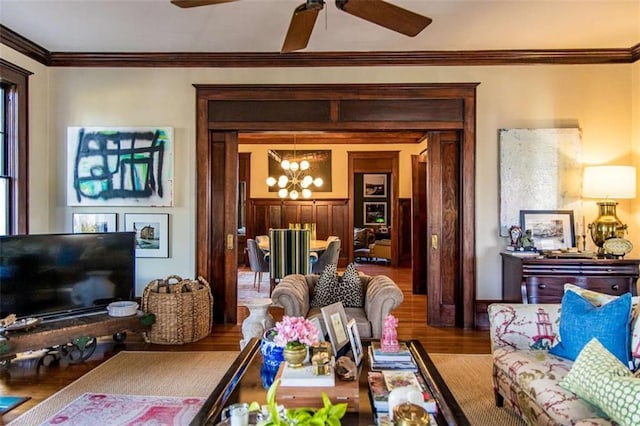 living area featuring ceiling fan with notable chandelier, crown molding, and wood finished floors