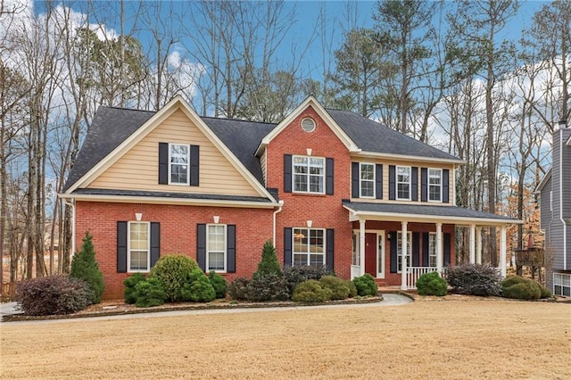 view of front of property featuring a porch, brick siding, and a front lawn