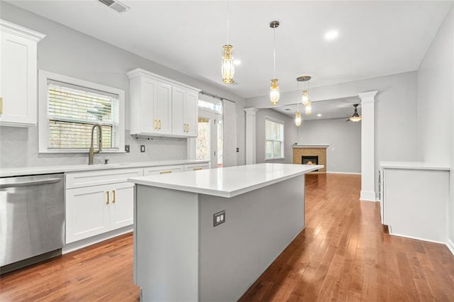 kitchen with a wealth of natural light, a center island, white cabinets, and stainless steel dishwasher