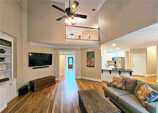 215 Settindown Ct, Roswell, GA 30075 - living area featuring light wood-style flooring, ceiling fan, a towering ceiling, and ornamental molding