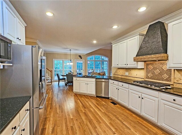 215 Settindown Ct, Roswell, GA 30075 - kitchen with appliances with stainless steel finishes, custom exhaust hood, light wood finished floors, a peninsula, and white cabinetry