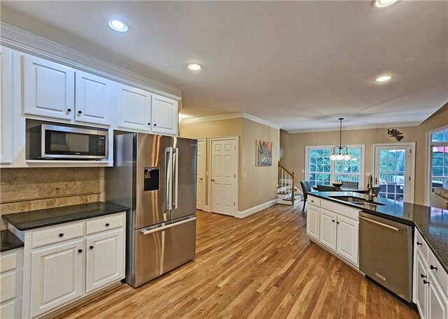 215 Settindown Ct, Roswell, GA 30075 - kitchen with appliances with stainless steel finishes, ornamental molding, dark countertops, white cabinetry, and plenty of natural light
