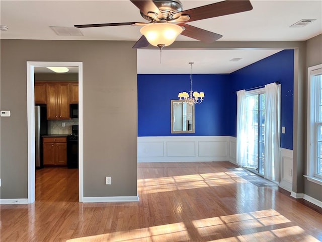 unfurnished room with ceiling fan with notable chandelier and light wood-type flooring