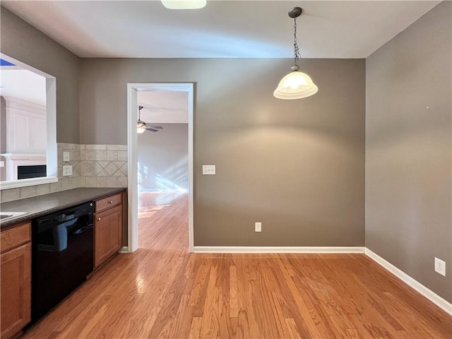 kitchen with ceiling fan, black dishwasher, light wood-type flooring, and hanging light fixtures