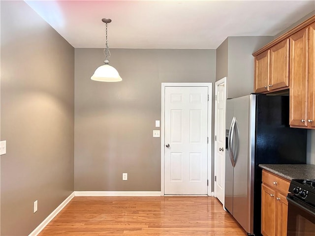 kitchen featuring black range oven, decorative light fixtures, and light wood-type flooring